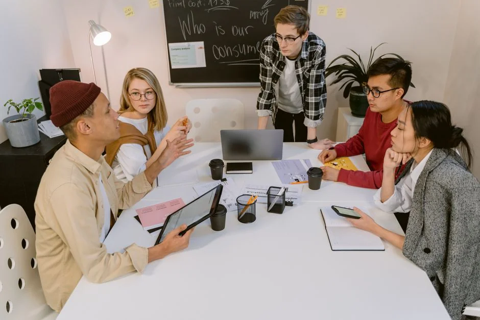 A diverse team collaborating on digital marketing strategies at a desk, using laptops and tablets.
